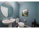 Stylish powder room features blue walls, a pedestal sink, and a modern oval mirror at 15476 W 64Th Loop # C, Arvada, CO 80007