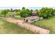 View of horse barn with fenced riding area and large green trees at 7583 W Trail South Dr, Littleton, CO 80125