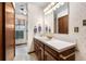 Well-lit bathroom featuring a vanity with drawers and cabinets, a mirror and floral wallpaper at 7583 W Trail South Dr, Littleton, CO 80125