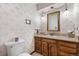 Charming half bathroom featuring floral wallpaper, a vanity with oak cabinets, and decorative lighting at 7583 W Trail South Dr, Littleton, CO 80125