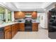 Well-maintained kitchen with wood cabinetry, practical appliances, and a view of the adjacent living area at 7583 W Trail South Dr, Littleton, CO 80125