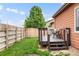 Inviting backyard deck with a table and chairs overlooks a well-maintained lawn with a wooden fence at 1836 Taos St, Brighton, CO 80603