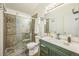 Bathroom featuring a tiled shower with glass door, toilet, sink, and white cabinets at 1111 S Garrison St # 202, Lakewood, CO 80232