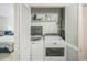 Laundry room features a white, front-loading washer and dryer and white shelving with supplies at 1111 S Garrison St # 202, Lakewood, CO 80232