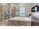 Bright bathroom featuring a glass shower, soaking tub, and neutral finishes at 6715 Raritan Dr, Denver, CO 80221