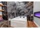 Luxurious bathroom showcasing a large soaking tub, stone-look accent wall, and sleek decor at 6715 Raritan Dr, Denver, CO 80221
