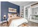 Cozy bedroom featuring a blue accent wall, decorative shelving, and an inviting bed with stylish linens at 6715 Raritan Dr, Denver, CO 80221