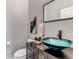 Chic powder room featuring unique vessel sink, dark vanity, and decorative mirror at 6715 Raritan Dr, Denver, CO 80221