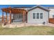 Backyard features a hot tub under a pergola, a grill, stone patio, and green lawn at 12510 Fisher St, Englewood, CO 80112
