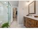 Bathroom with double sinks, wood cabinets, large mirrors, and a glass shower to the left at 12510 Fisher St, Englewood, CO 80112
