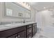 A clean bathroom featuring double sinks, granite countertops, dark cabinets, and a tub shower at 12510 Fisher St, Englewood, CO 80112
