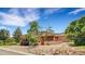 A charming single-story home boasts a unique exterior design with a stone landscape and well-kept lawn at 6201 Rain Dance Trl, Littleton, CO 80125