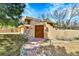 Charming home with a stucco wall, gated entry, and brick pathway leading to the front door at 6201 Rain Dance Trl, Littleton, CO 80125