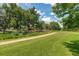 Expansive green space with a paved path, mature trees, and lush vegetation at 2500 S York St # 401, Denver, CO 80210