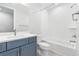 Bright bathroom featuring a blue vanity, tub with white tiled walls and modern fixtures at 9688 Winterset Cir, Littleton, CO 80125