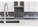 Modern kitchen with stainless steel appliances and gray backsplash with bright white cabinets at 9688 Winterset Cir, Littleton, CO 80125