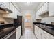 Galley kitchen with white cabinetry, black countertops, and stainless steel appliances at 7995 E Mississippi Ave # 24, Denver, CO 80247