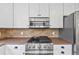 A close up of a modern kitchen with stainless appliances, gas range and white cabinets at 30866 Kings Valley Way, Conifer, CO 80433