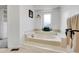 Bright bathroom featuring a soaking tub with tile surround and natural light from a window at 12718 W 84Th Dr, Arvada, CO 80005