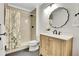 Bathroom featuring a tiled shower, modern vanity, and decorative mirror at 12718 W 84Th Dr, Arvada, CO 80005