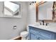 Cozy bathroom has a blue vanity with marble countertop, wood mirror frame, and shiplap walls at 12718 W 84Th Dr, Arvada, CO 80005