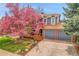 Charming two-story home with a beautiful blooming tree in the front yard and a two car garage at 12718 W 84Th Dr, Arvada, CO 80005