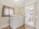 Functional laundry room with washer, dryer, and access to a tiled bathroom at 1340 Iola St, Aurora, CO 80010