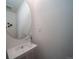 Modern powder room featuring a sleek sink with a chrome faucet and a round mirror at 13545 E 103Rd Ave, Commerce City, CO 80022