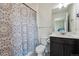 Well-lit bathroom with a vanity, toilet, shower with a patterned blue and white shower curtain, and neutral-colored walls at 7498 E 157Th Pl, Thornton, CO 80602