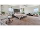 Spacious bedroom with a large bed, desk area, many plants, light-colored walls and carpet, and a ceiling fan at 7498 E 157Th Pl, Thornton, CO 80602