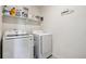 A laundry room featuring a front-load washer and dryer with a shelf of cleaning supplies and a 