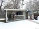 This backyard features a covered patio, a deck, and a storage shed, all covered in a layer of snow at 1641 S Zenobia St, Denver, CO 80219