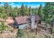 Elevated view of mountain home with stone chimney and deck surrounded by lush forest at 28669 Mountain View Rd, Conifer, CO 80433