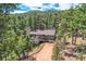 Aerial view showcases a peaceful home nestled amidst lush trees with a long driveway at 28669 Mountain View Rd, Conifer, CO 80433
