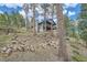 The home features a stone chimney, forest views, and a quaint deck for outdoor enjoyment at 28669 Mountain View Rd, Conifer, CO 80433