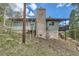A charming home boasts a stone chimney, green siding, and a deck, nestled into a gently sloping hillside at 28669 Mountain View Rd, Conifer, CO 80433
