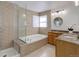Bathroom featuring tile surround soaking tub, separate shower and dual sinks on granite counters at 6055 W Warren, Lakewood, CO 80227