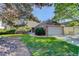 Charming brick home with a well-manicured lawn and a two-car garage, framed by mature trees at 6055 W Warren, Lakewood, CO 80227