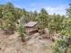 Aerial view of home surrounded by trees; also features stone walls and multi-level wooden decks at 30938 Niakwa Rd, Evergreen, CO 80439