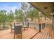 Outdoor deck features a dining table and chairs with a view of the wooded exterior at 30938 Niakwa Rd, Evergreen, CO 80439