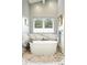 Elegant bathroom featuring marble tile, a freestanding tub, and a large window at 2635 Pierce St, Wheat Ridge, CO 80214