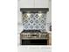 Close up of a modern gas range, beautiful backsplash and stainless steel hood vent at 2635 Pierce St, Wheat Ridge, CO 80214