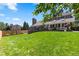 Well-maintained backyard featuring a large deck, mature trees, and lush green lawn at 7750 S Glencoe Way, Centennial, CO 80122