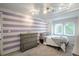 Bright bedroom with purple striped accent wall, double window, and dresser at 7750 S Glencoe Way, Centennial, CO 80122