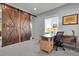 This office features rustic barn doors, gray walls, and a bright window for a warm and productive workspace at 4781 Basalt Ridge Cir, Castle Rock, CO 80108
