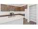 Modern kitchen featuring stainless appliances, brown cabinetry, quartz countertops, and a walk-in pantry for optimal storage at 13392 E 110Th Way, Commerce City, CO 80022