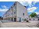 Back view of gray townhomes shows garages and modern design, plus a small blue shed with a beautiful blue sky above at 3520 W Conejos Pl # 14, Denver, CO 80204