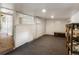 Unfinished basement with dark gray carpet, white walls, and a white entry door at 3134 W Center Ave, Denver, CO 80219