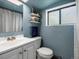 Bathroom with blue painted walls, white sink and toilet, and a window to the outside at 3134 W Center Ave, Denver, CO 80219