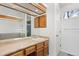 Bathroom featuring wooden cabinets, large mirror over sink, and a white door at 3819 S Waco St, Aurora, CO 80013